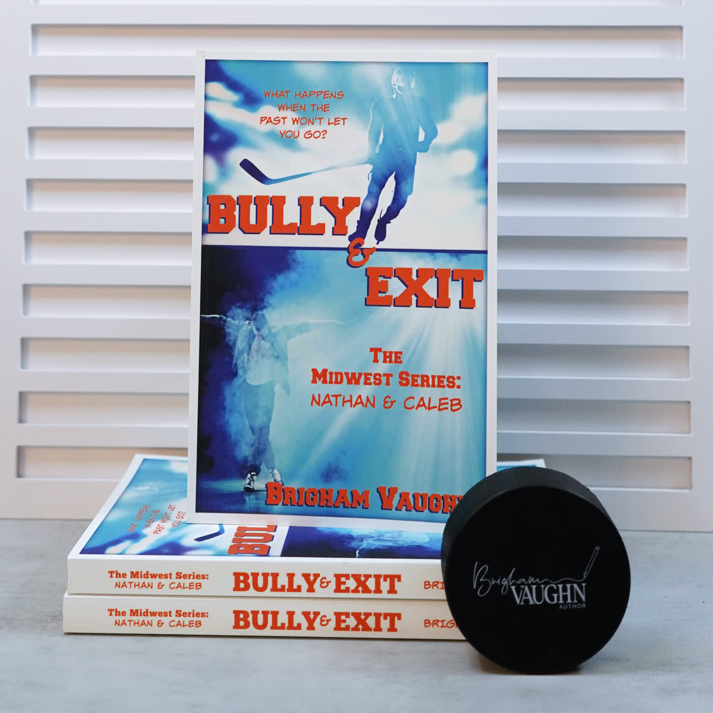 Stack of books titled 'Bully & Exit' by Brigham Vaughn with a branded puck on a light background.