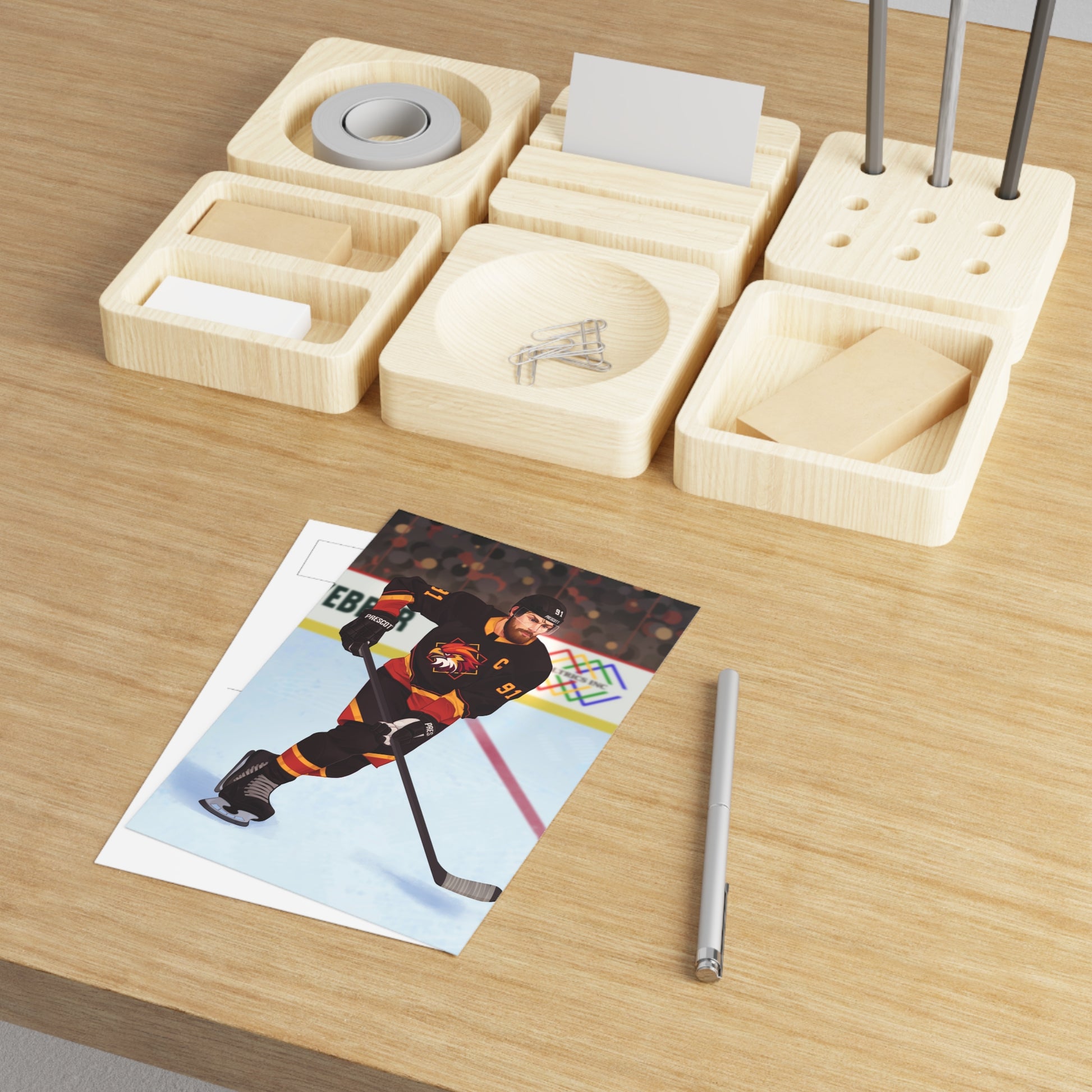 4 by 6 inch art print of Boston Harriers illustrated hockey player in action on an ice rink with a colorful background. Connor O'Shea from Goaltender Interference by Brigham Vaughn on a wooden table with a pen