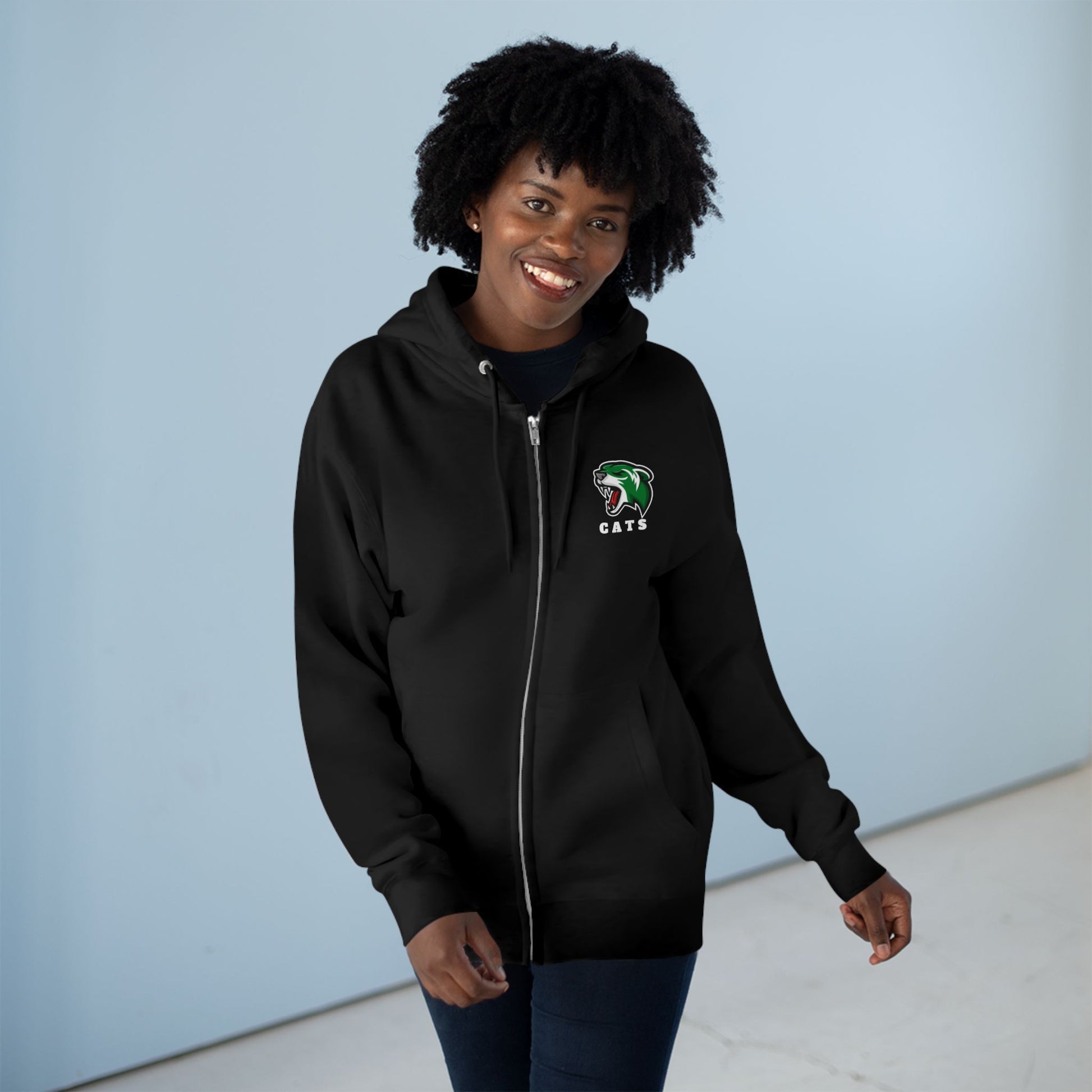 Woman with brown skin and natural black hair wearing Black Noah Boucher Toronto Fisher Cats Zip Hoodie and jeans