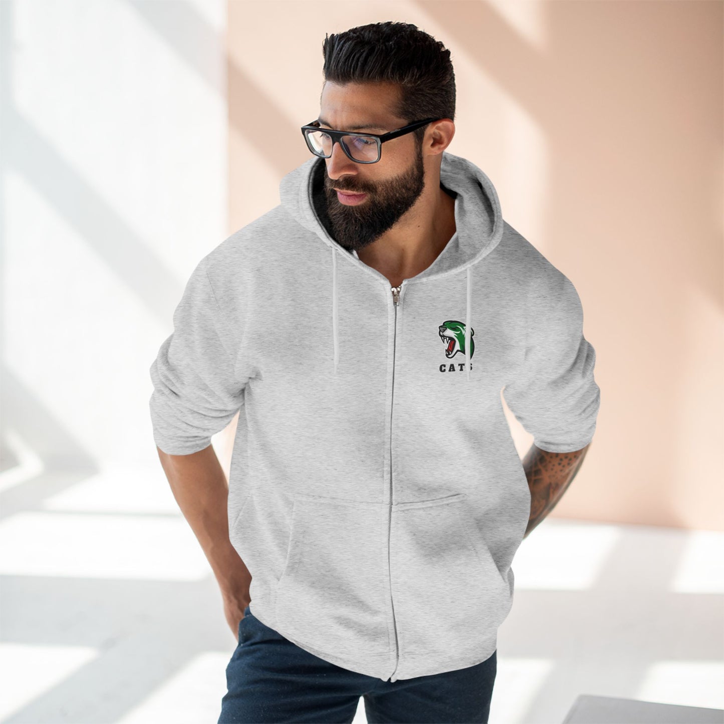 Man with brown skin and black hair/beard wearing glasses, Heather Grey Noah Boucher Toronto Fisher Cats Zip Hoodie, and jeans. 