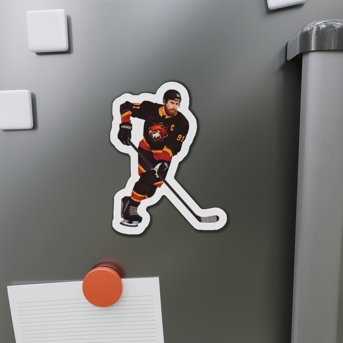 Illustration of a hockey player in a black, red, and gold uniform with a hawk on the chest and C above it. Depicting Connor O'Shea from mm hockey romance Goaltender Interference Book #1 in Brigham Vaughn's Scoring Chances Series. Displayed  refrigerator with other magnets and a paper holder.