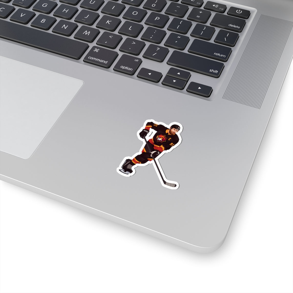 Illustration of a hockey player in a black, red, and gold uniform with a hawk on the chest and C above it. Depicting Connor O'Shea from mm hockey romance Goaltender Interference Book #1 in Brigham Vaughn's Scoring Chances Series. Displayed on laptop