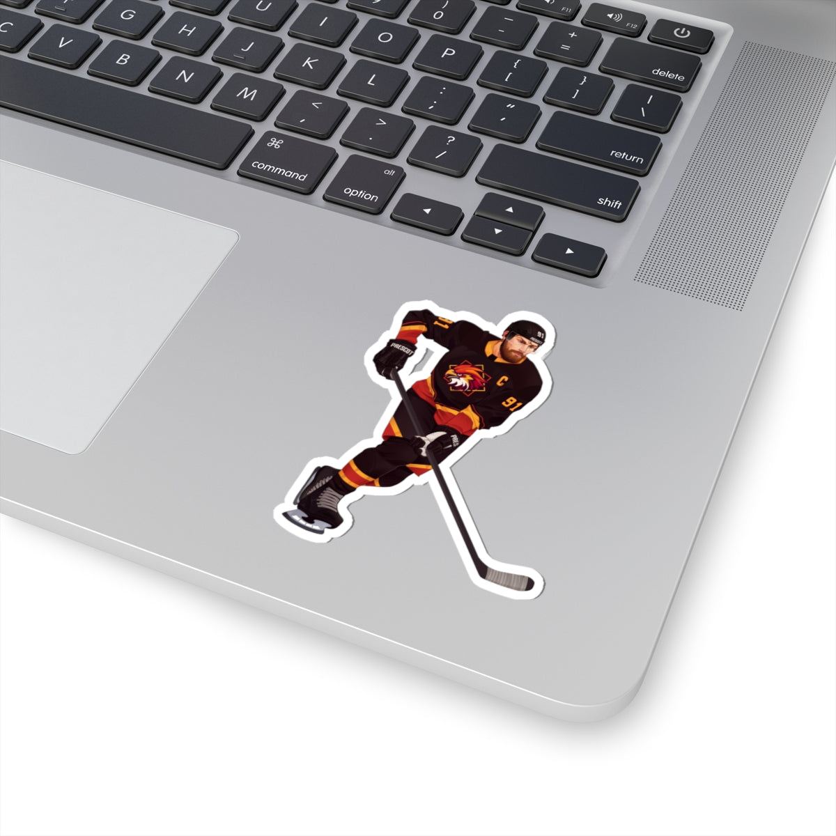 Illustration of a hockey player in a black, red, and gold uniform with a hawk on the chest and C above it. Depicting Connor O'Shea from mm hockey romance Goaltender Interference Book #1 in Brigham Vaughn's Scoring Chances Series. Displayed on laptop