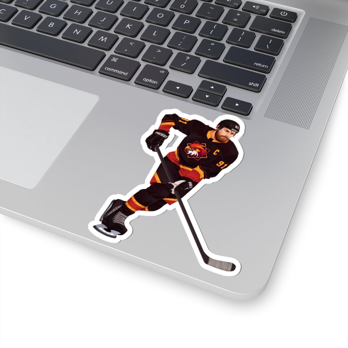 Illustration of a hockey player in a black, red, and gold uniform with a hawk on the chest and C above it. Depicting Connor O'Shea from mm hockey romance Goaltender Interference Book #1 in Brigham Vaughn's Scoring Chances Series. Displayed on laptop