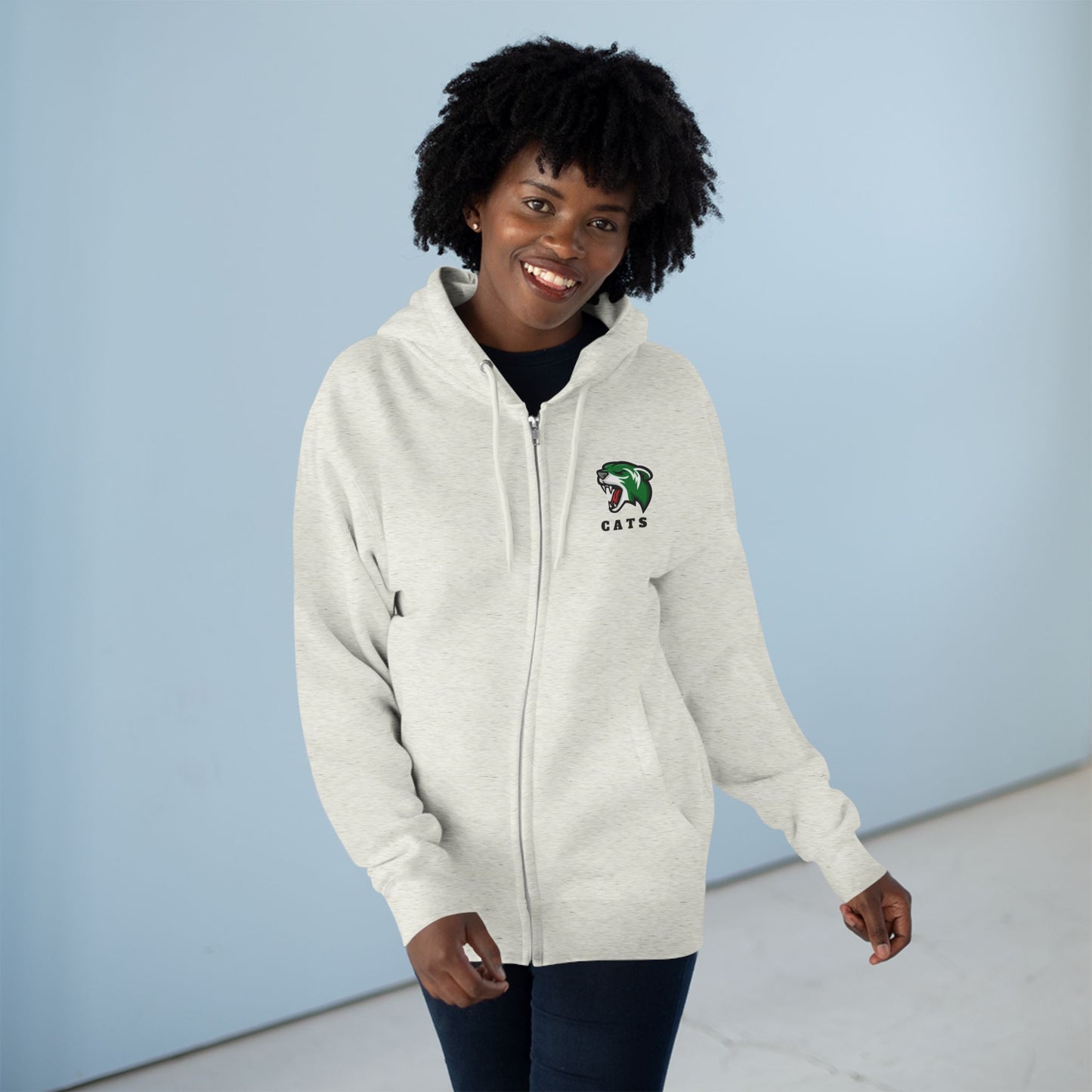 Woman with brown skin and natural black hair wearing Oatmeal Heather Noah Boucher Toronto Fisher Cats Zip Hoodie and jeans
