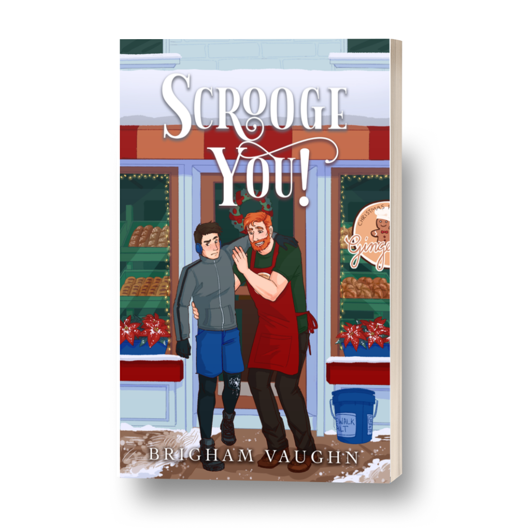 3D mockup of Scrooge You! Paperback, featuring an illustrated image of of a ginger haired man in a T-shirt and jeans and apron helping a shorter, younger dark haired man in running gear with an injured knee in front of Ginger's Bread's Bakery