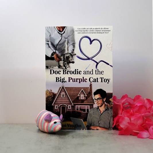 Signed paperback book cover of 'Doc Brodie and the Big, Purple Cat Toy' with a cat toy and pink flowers on a white surface.
