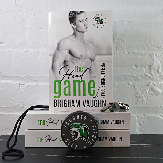 Signed paperback book titled 'The Head Game' by Brigham Vaughn with a hockey puck and whistle on a white brick wall background.