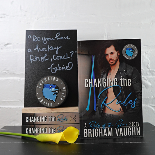 Signed paperback book titled 'Changing the Rules' by Brigham Vaughn with yellow flower and chalkboard with a quote from the book. 
