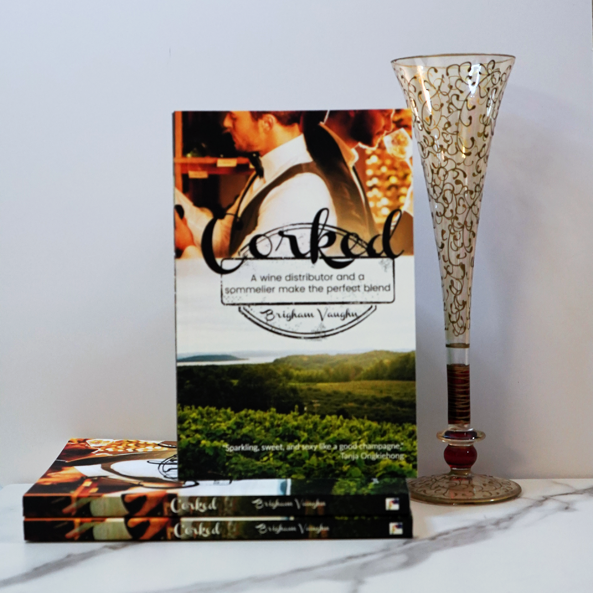 Stack of signed paperback books titled 'Corked' with a champagne flute against a white background. 