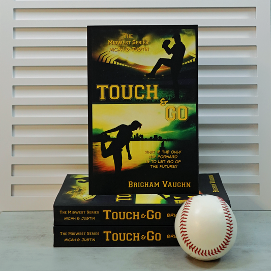 Stack of signed paperback books titled 'Touch & Go' by Brigham Vaughn with a baseball on a white surface.