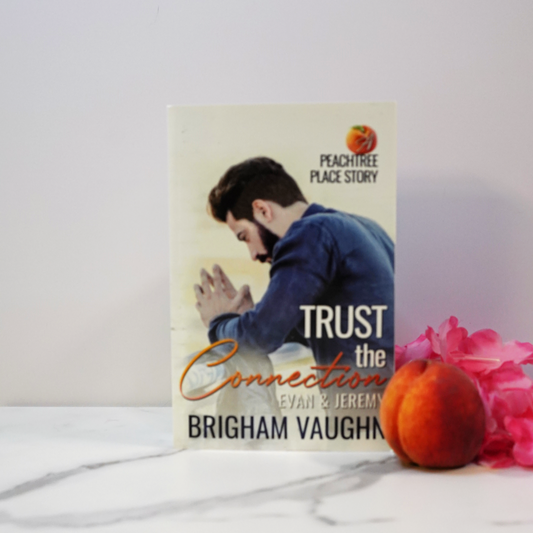 Signed paperback book titled 'Trust the Connection' by Brigham Vaughn with a peach and pink flowers on a white surface.