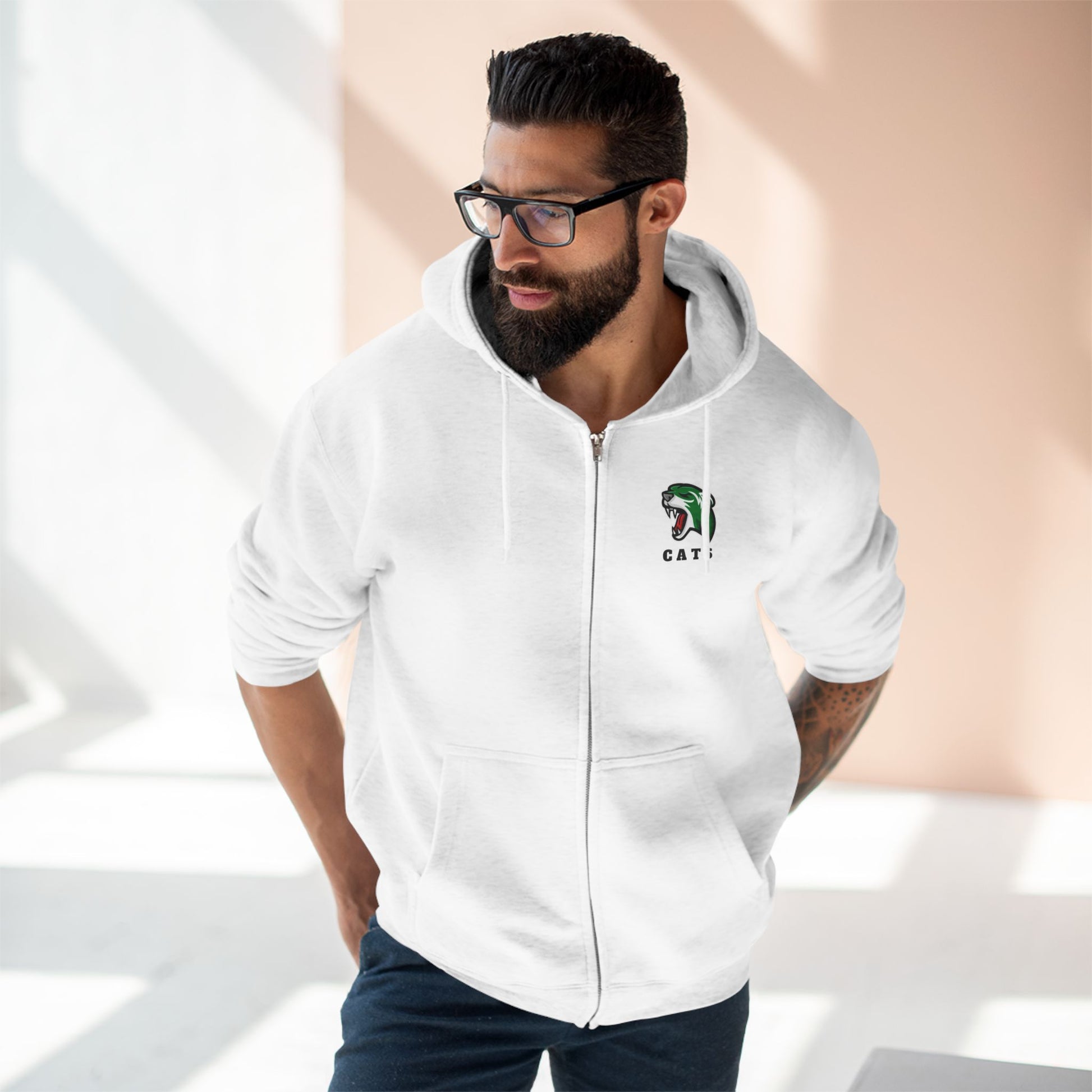 Man with brown skin and black hair/beard wearing glasses and white Noah Boucher Toronto Fisher Cats Zip Hoodie with jeans
